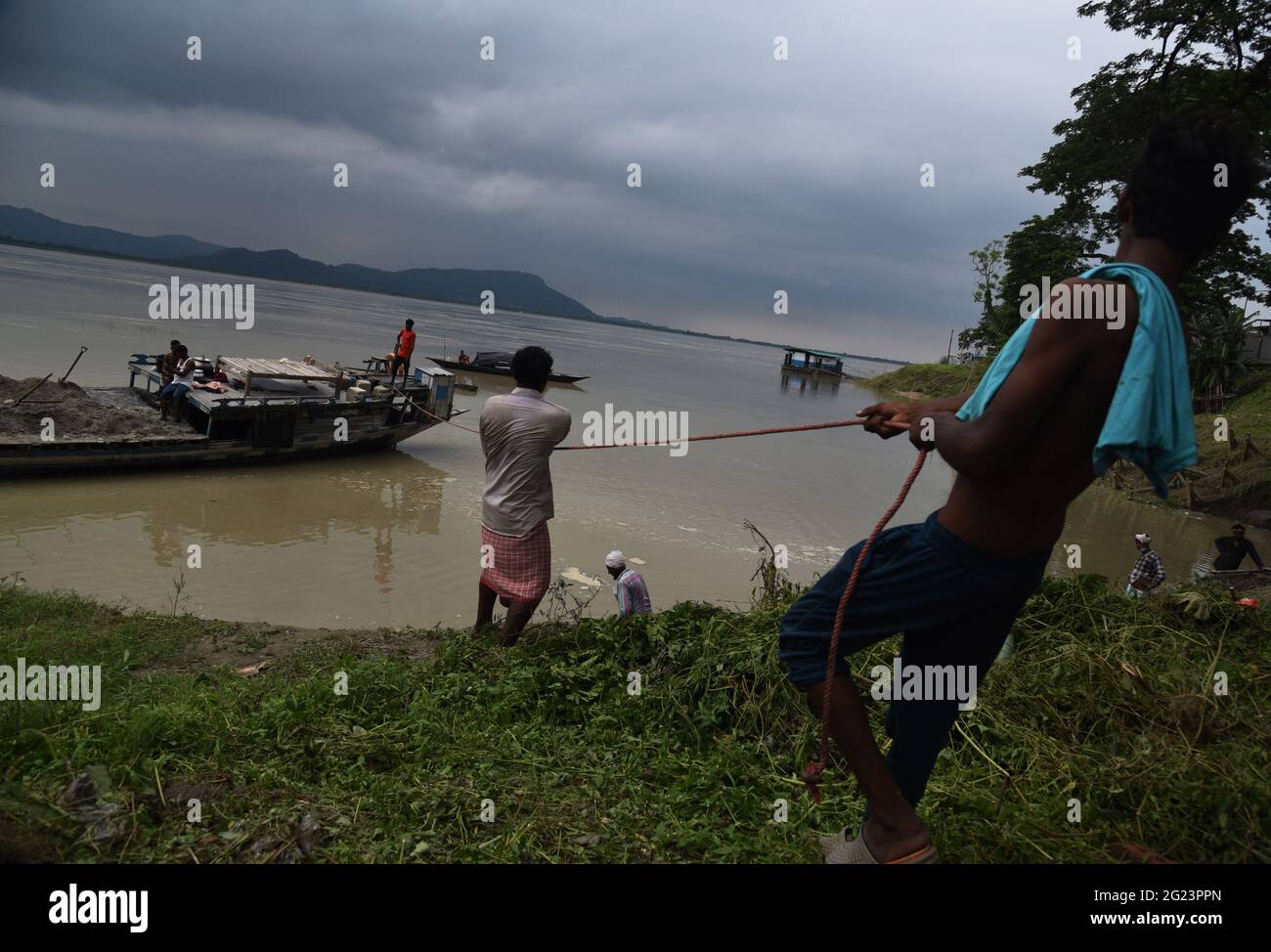 Guwahati, Guwahati, India. 8 Giugno 2021. Lavoratori tira una barca a riva che ha portato sabbie a mettere sulla riva del fiume Brahmaputra riempiendo in sacchi per controllare l'erosione del suolo prima della stagione monsone a Guwahati Assam India su Martedì 8 giugno 2021 Credit: Dasarath Deka/ZUMA Wire/Alamy Live News Foto Stock