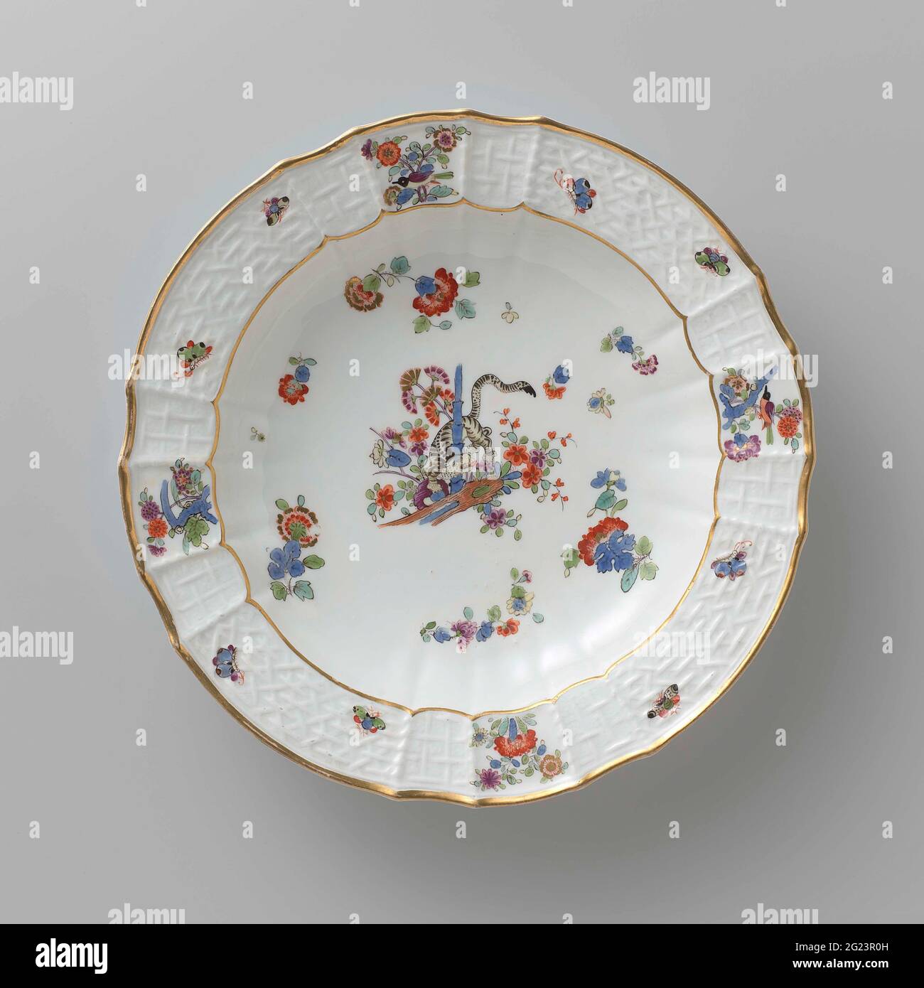 Tavola per zuppe, dipinta in modo multiplo con un decor kakiemon. Zuppa di porcellana dipinta. La piastra ha un bordo rigato e scalettato. La piastra è dipinta con una tigre, che ruota tra i fiori intorno a un gambo di bambù, blums Indiani sparsi, farfalle e rami con uccelli. Il bordo è decorato con il motivo 'Altbrandenstein'. La piastra è stata contrassegnata. Foto Stock