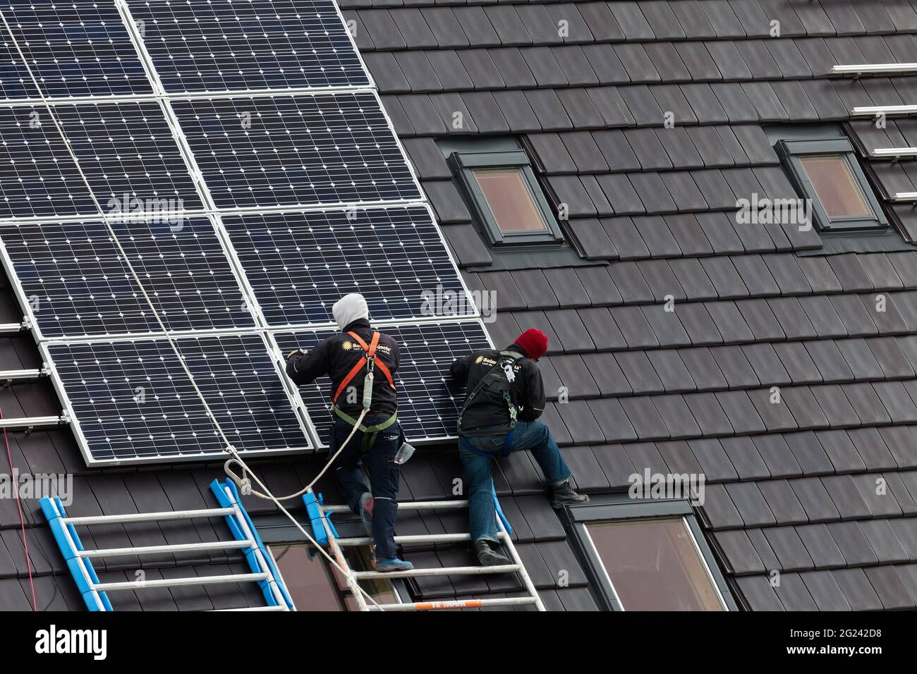 Operai edili che installano pannelli solari sui tetti di case di nuova costruzione Foto Stock