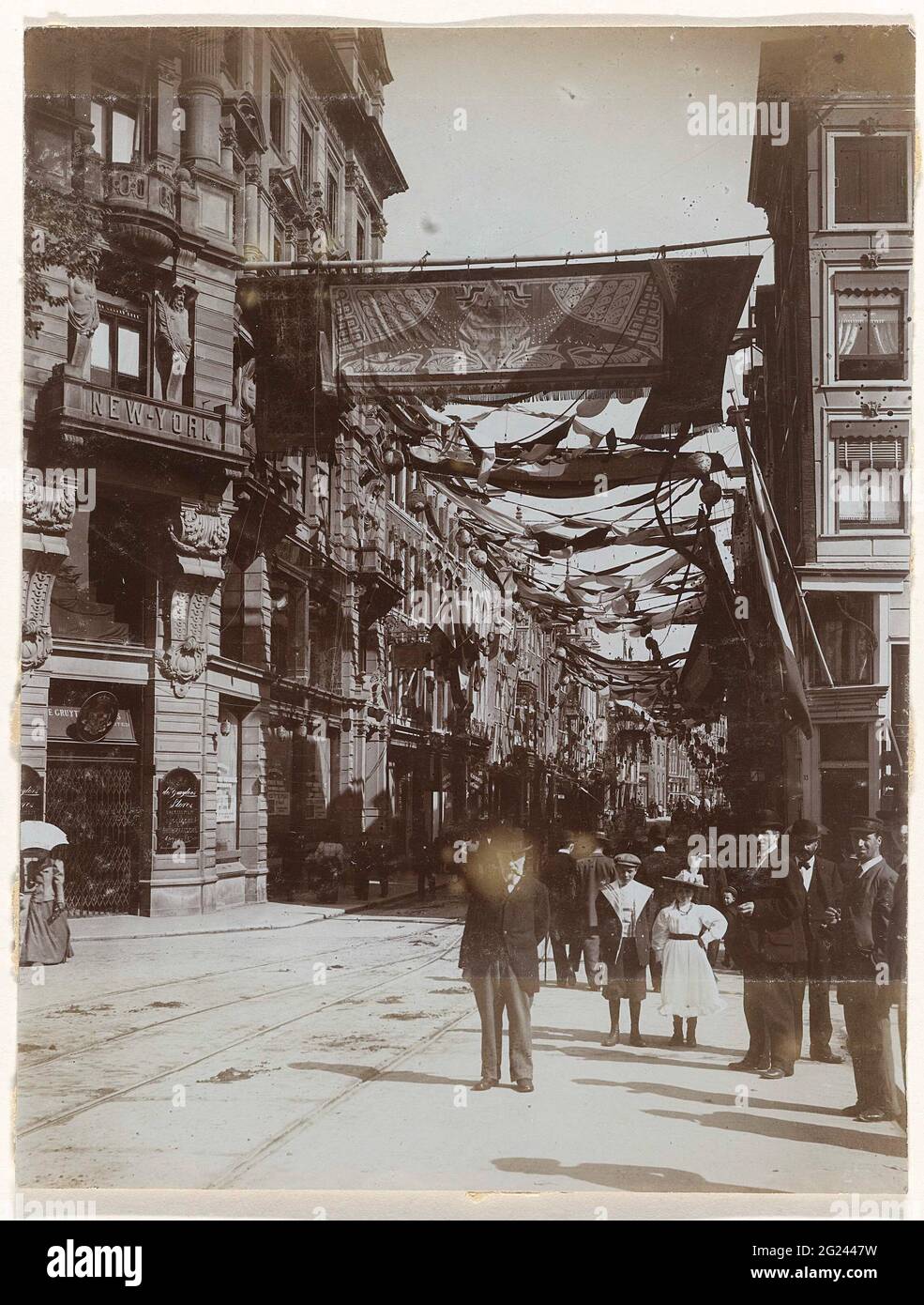 La Leidsestraat al culmine del Keizersgracht, decorata il più possibile in occasione dell'inaugurazione della Regina Wilhelmina, Amsterdam, Paesi Bassi. Il Leidsestraat con all'angolo del Keizersgracht l'edificio della New York Life Insurance Company, con al piano terra 'De Gruyter's Stores'. La decorazione è possibile in occasione dell'inaugurazione della Regina Wilhelmina, Amsterdam, Paesi Bassi. Persone diverse in primo piano. Foto Stock