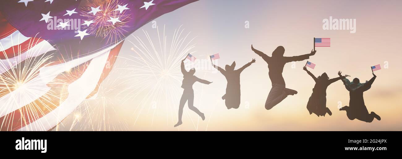Silhouettes gruppo di persone che detengono la bandiera del salto degli Stati Uniti in America festeggiano il 4 luglio fuochi d'artificio. Sventolando Happy American Flags al Tramonto. Folla Foto Stock