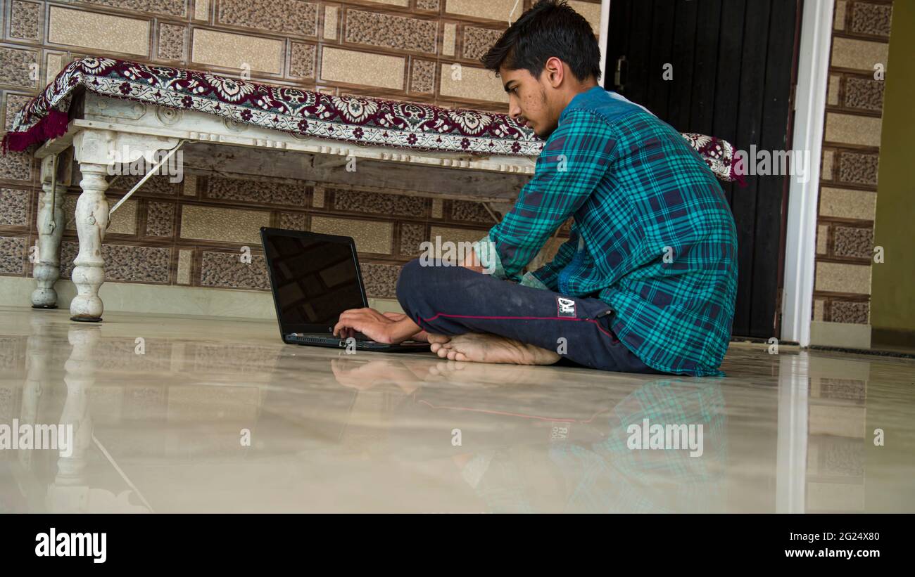 Un ragazzo indiano che lavora da casa sul suo laptop. Concetto di lavoro da casa. Foto Stock