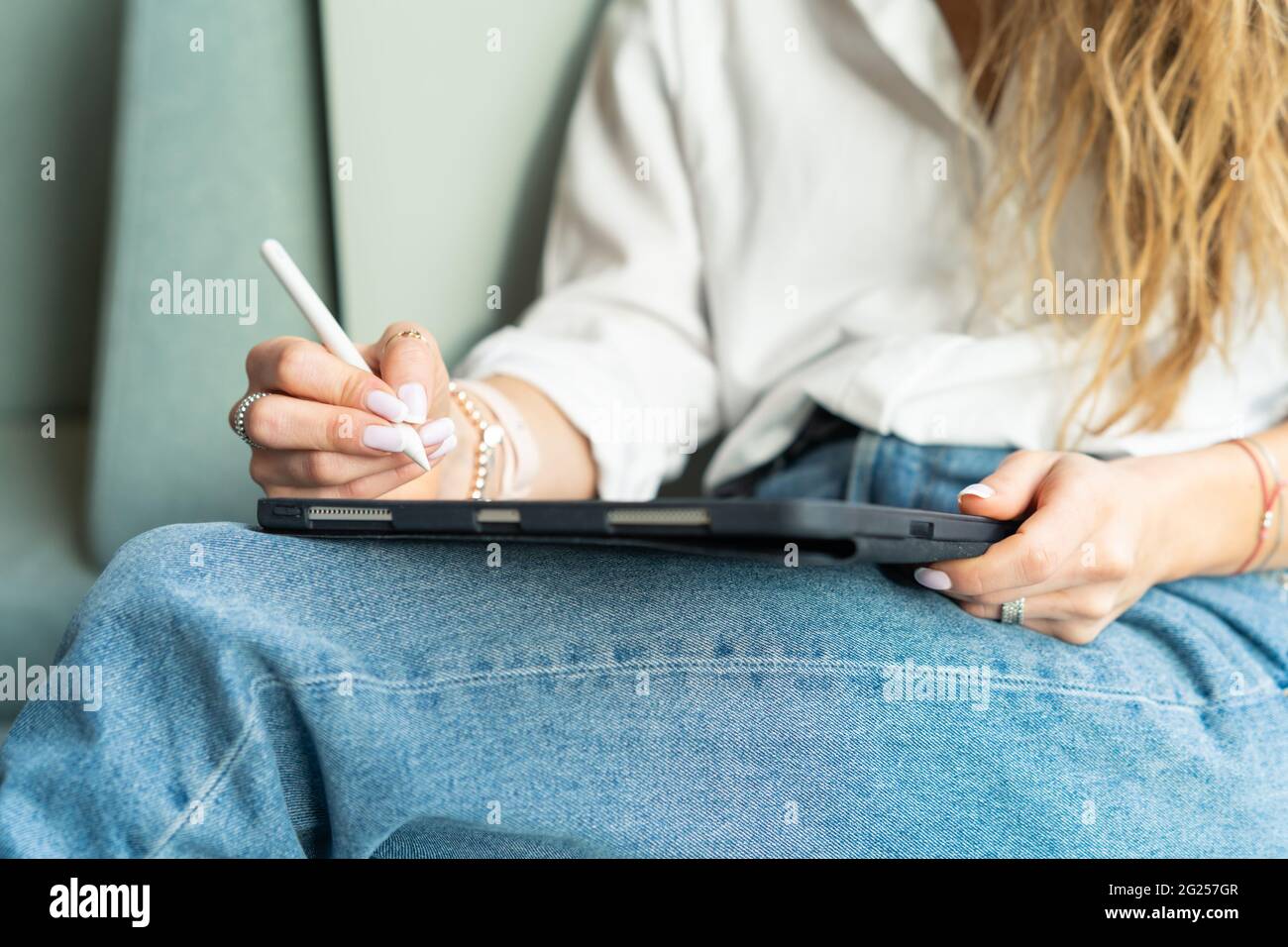 Donna seduta su un divano che lavora sul suo tablet Foto Stock