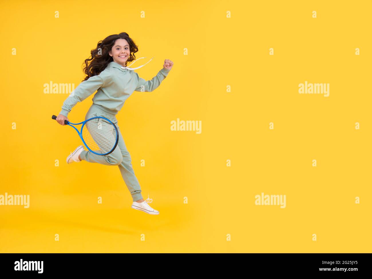felice salto energico bambino con racchetta da tennis che corre al successo, copy space, vendita shopping sportivo. Foto Stock