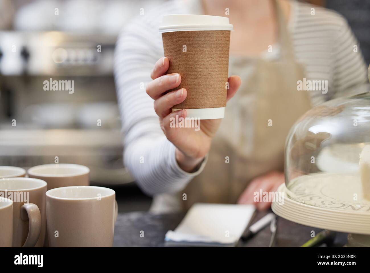 Primo piano di Female Worker in Cafe che serve caffè in tazza di carta sostenibile Foto Stock