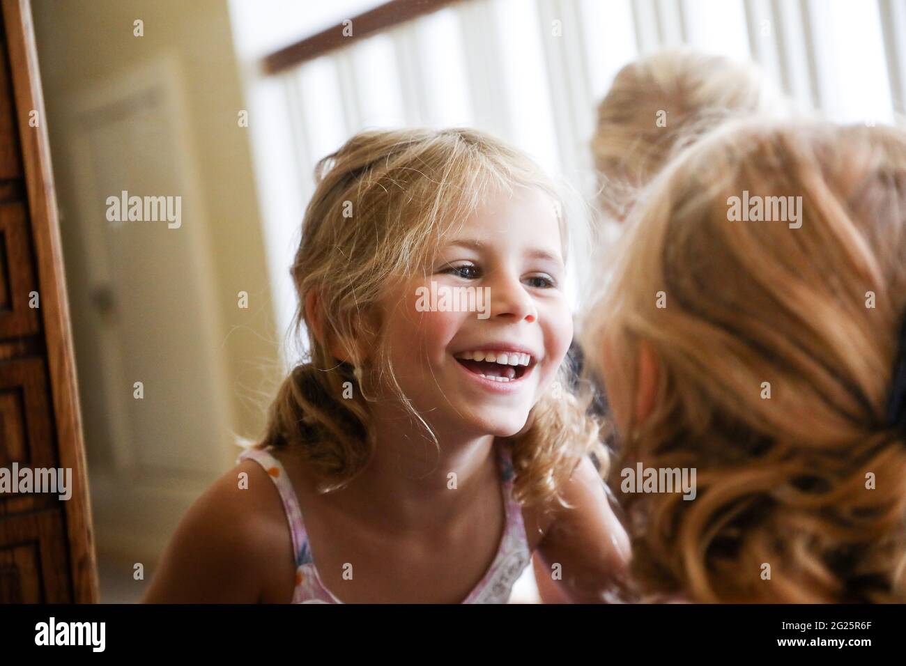 piccola ragazza che ride mentre guarda nello specchio Foto Stock