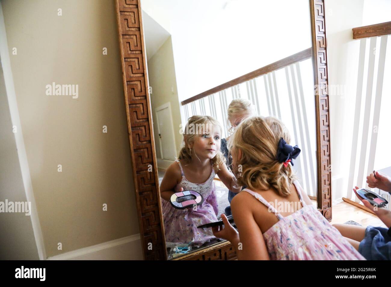 bambina che guarda se stessa nello specchio che indossa il trucco Foto Stock