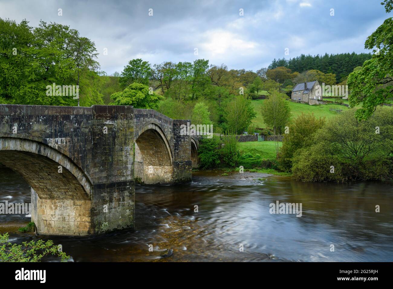 Vista panoramica, rurale sul fiume, sul ponte storico, in pietra, ad arco che attraversa le acque fluenti del fiume Wharfe - Ponte di Barden, Yorkshire Dales, Inghilterra, Regno Unito. Foto Stock