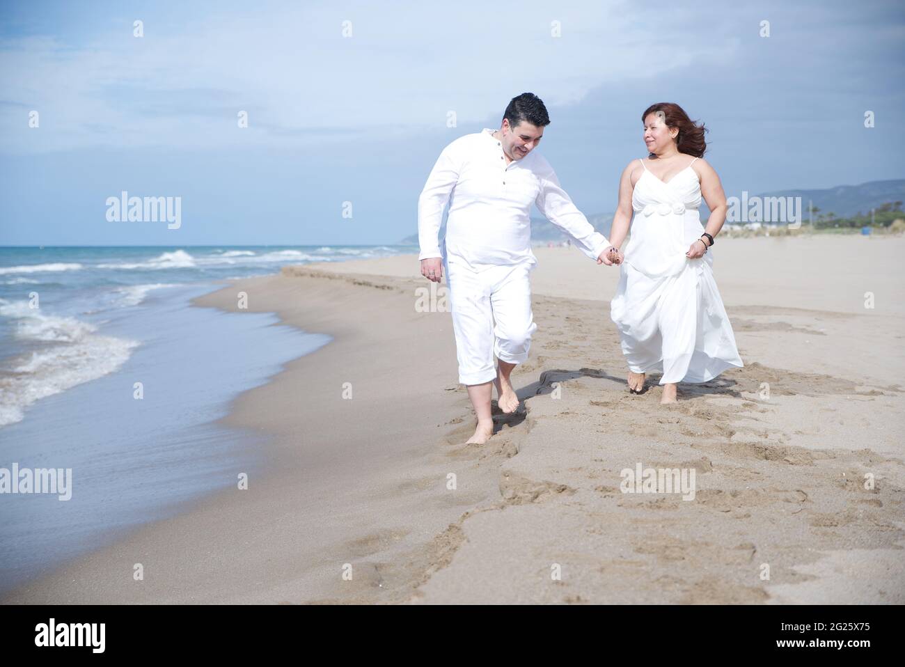 Coppia innamorata, uomo ispanico con donna latina, a piedi sulla spiaggia. Foto Stock