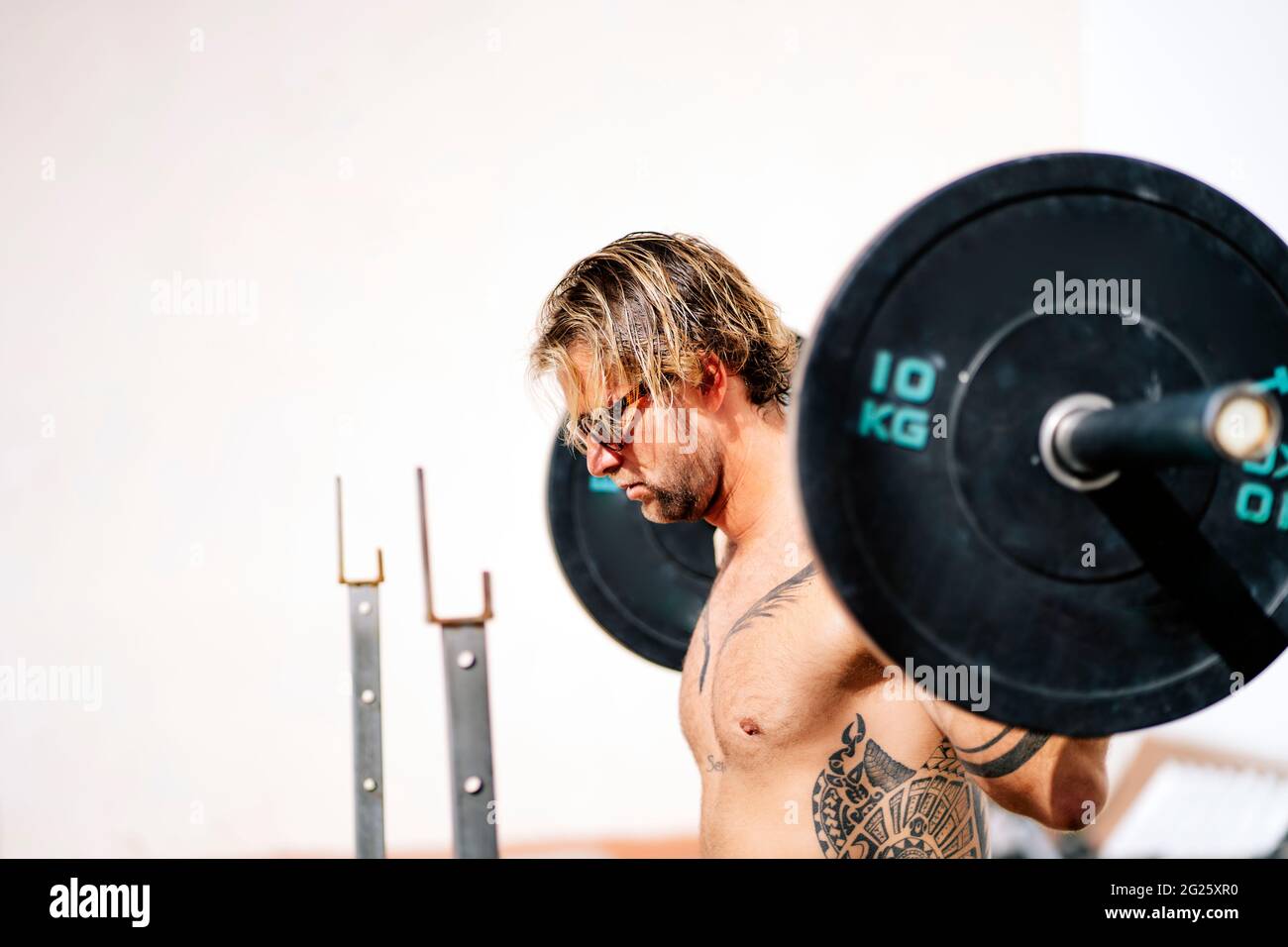 L'atleta biondo fa squats con i manubri Foto Stock