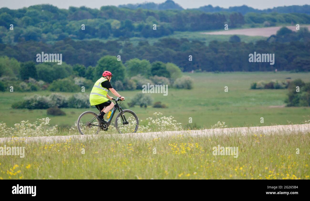 Il ciclista che indossa una giacca ad alta visibilità su una pedalata si fa strada attraverso una pista di pietra nell'area di addestramento militare di Salisbury Plain Foto Stock