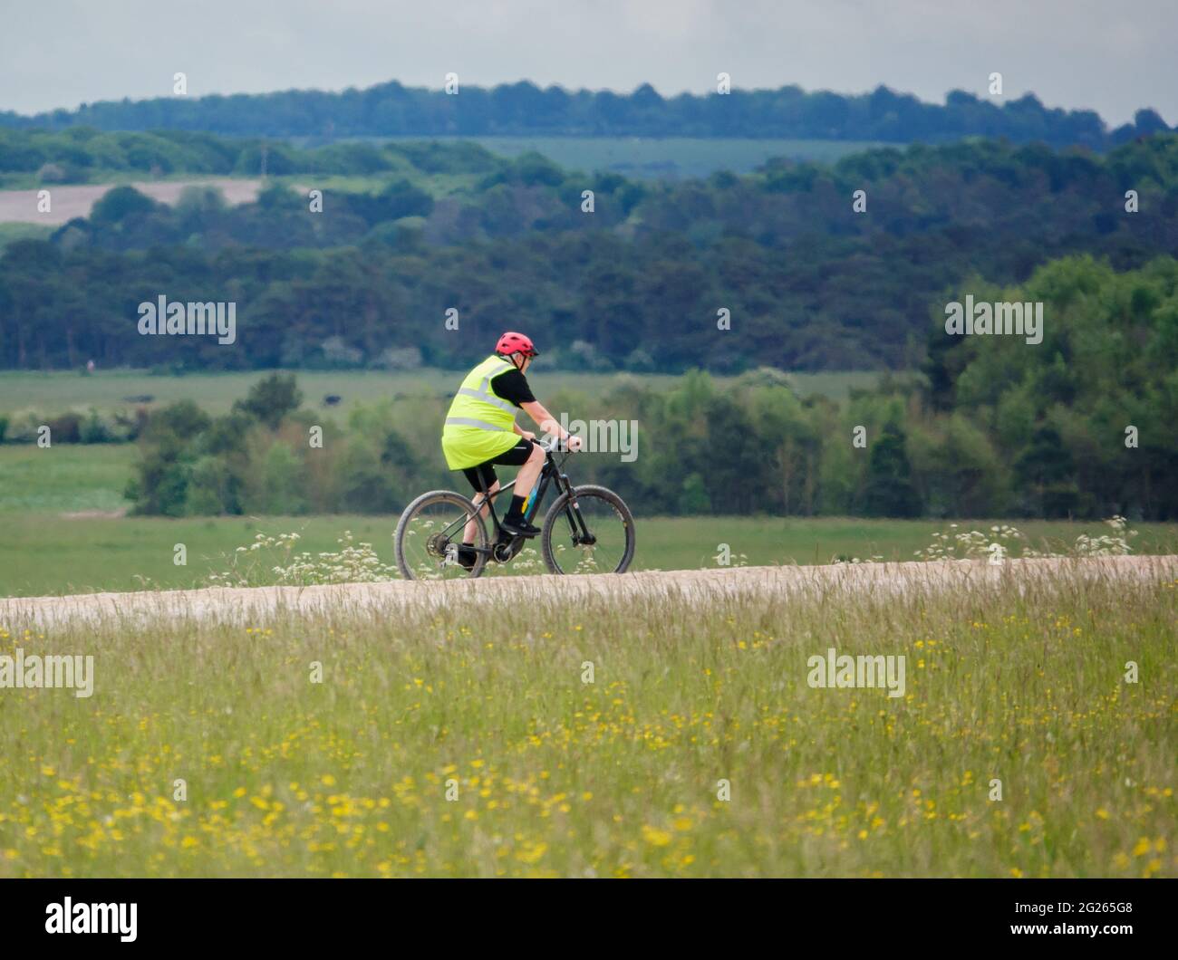 Il ciclista che indossa una giacca ad alta visibilità su una pedalata si fa strada attraverso una pista di pietra nell'area di addestramento militare di Salisbury Plain Foto Stock