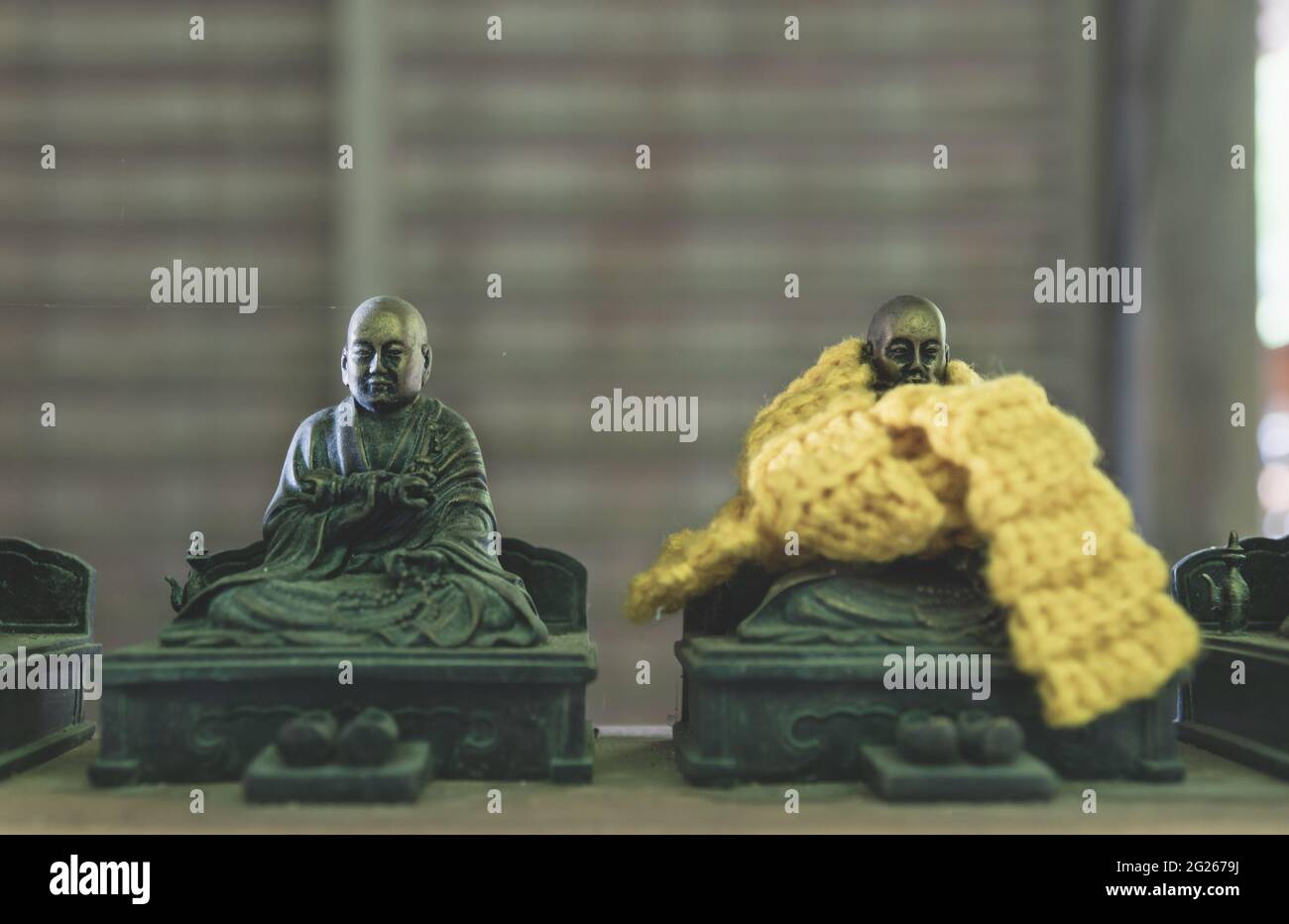 Piccole statue buddhiste in bronzo con offerte di sciarpe a maglia, che si ritiene possano realizzare i sogni dei fedeli nel tempio di Daisho-in a Miyajima, H. Foto Stock