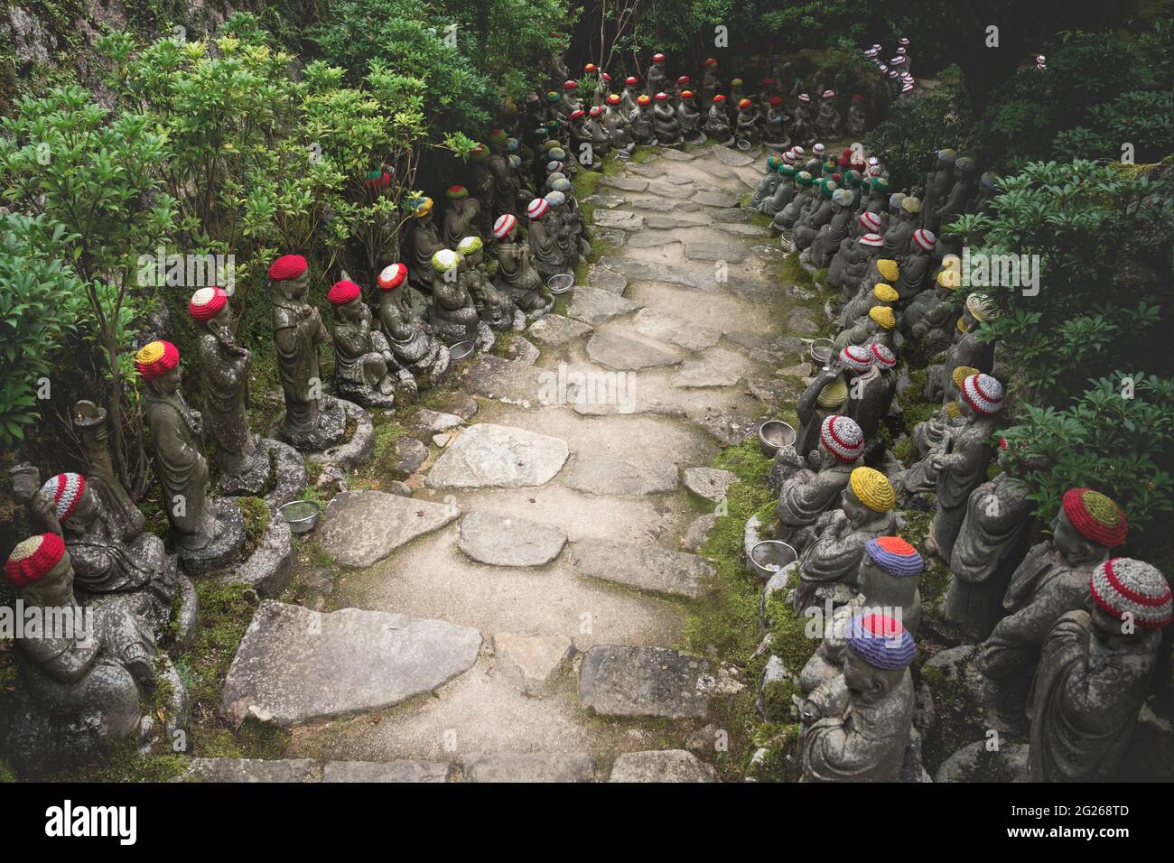 Percorso in pietra circondato da statue di Buddha con offerte di cappelli a maglia che rappresentano i primi 500 discepoli dello storico Buddha Shakyamuni al punto Foto Stock
