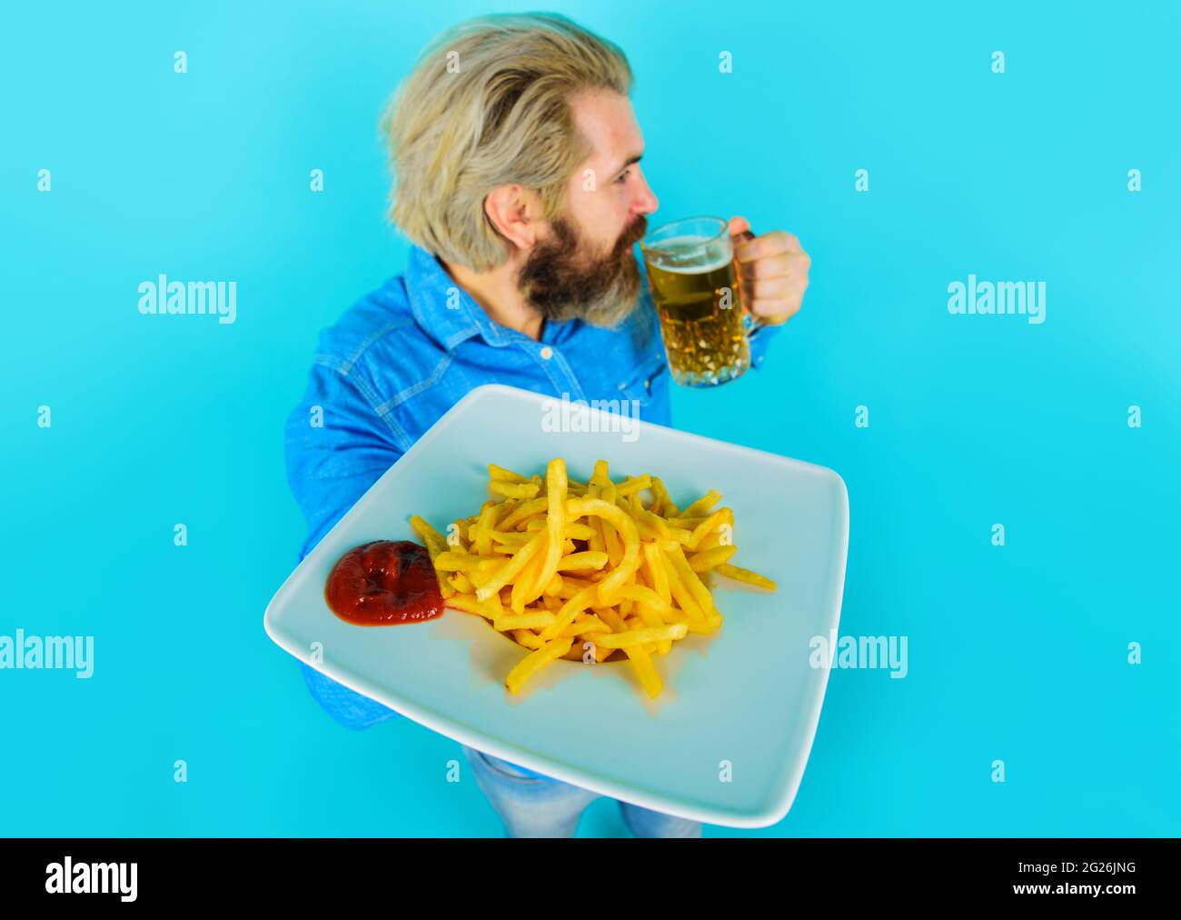 Uomo bearded con patatine fritte su piatto bevande birra. Snack al fast food. Messa a fuoco selettiva. Foto Stock