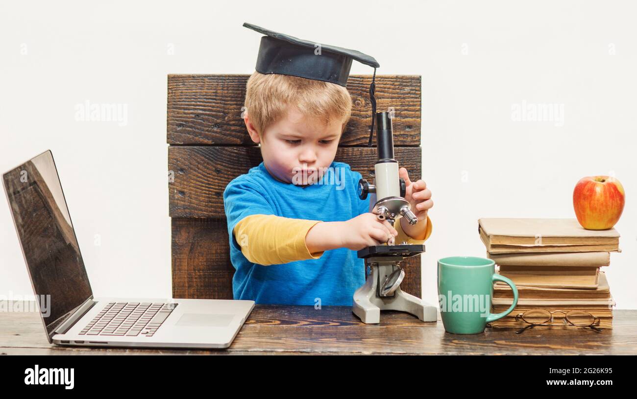 Scienza, Biologia, esperimento, Educazione. Un ragazzo intelligente e premuroso che lavora con il microscopio e il computer portatile. Foto Stock