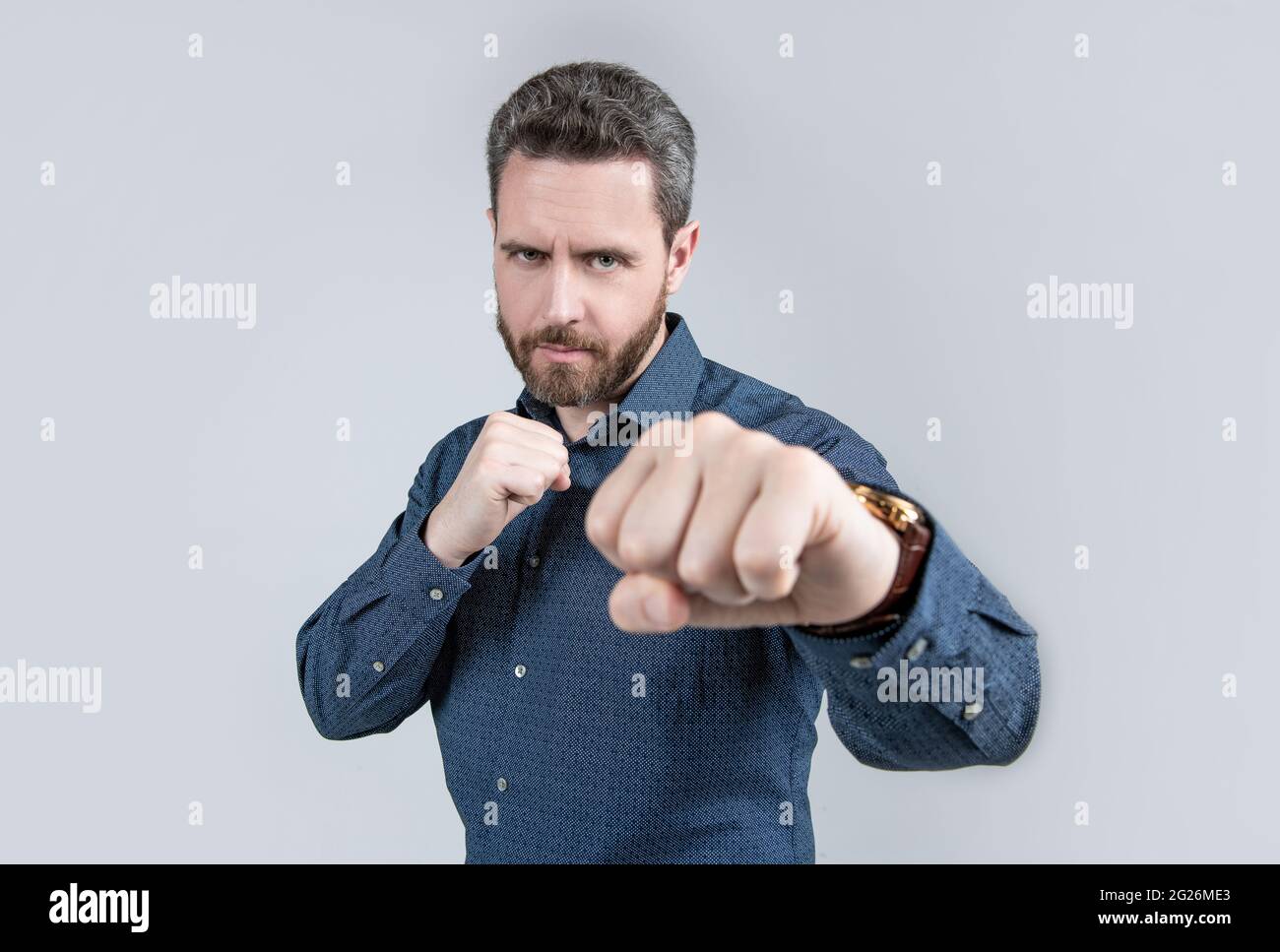 Uomo maturo stare in posizione di combattimento con pugni clenched in stile business casual, concorrenza Foto Stock