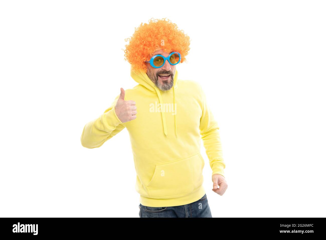 L'uomo divertente indossa funky parrucca capelli con gli occhiali da sole della festa mostrando pollici su gesto della mano, approvazione Foto Stock