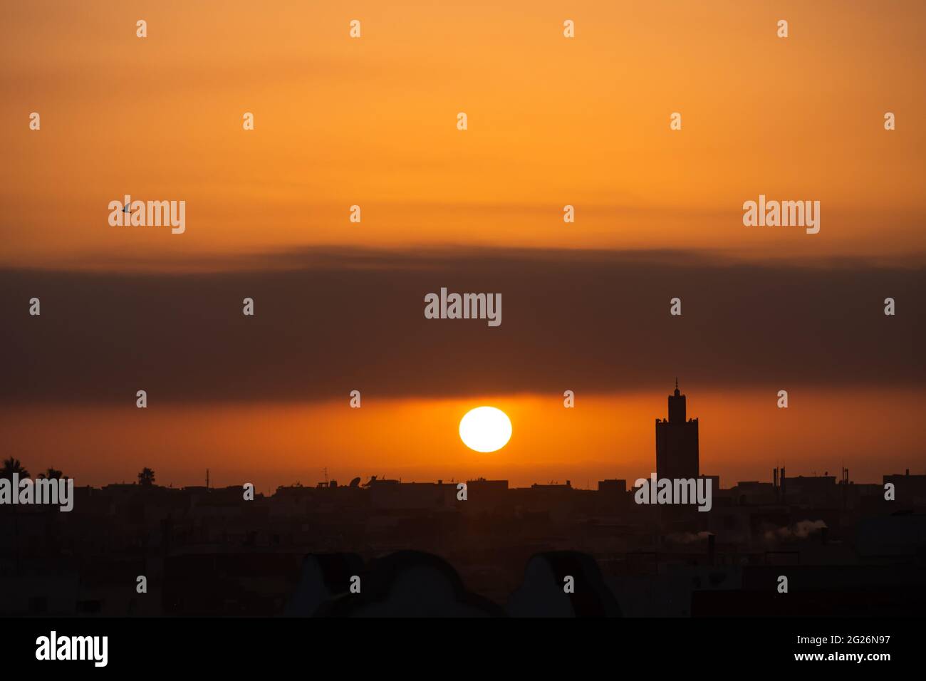 Tramonto visto dalla vecchia città portuale di El Jadida, Marocco, da dove si può osservare un minareto durante la chiamata alla preghiera. Foto Stock