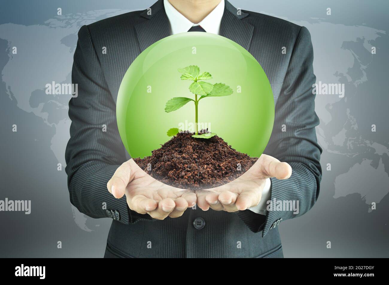 Uomo d'affari che tiene la segatura verde con il terreno all'interno della sfera - sviluppo sostenibile & concetto di conservazione Foto Stock