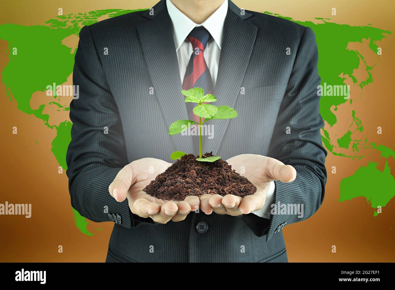 Uomo d'affari che tiene verde semenzatura con suolo - sviluppo sostenibile & concetto di conservazione Foto Stock