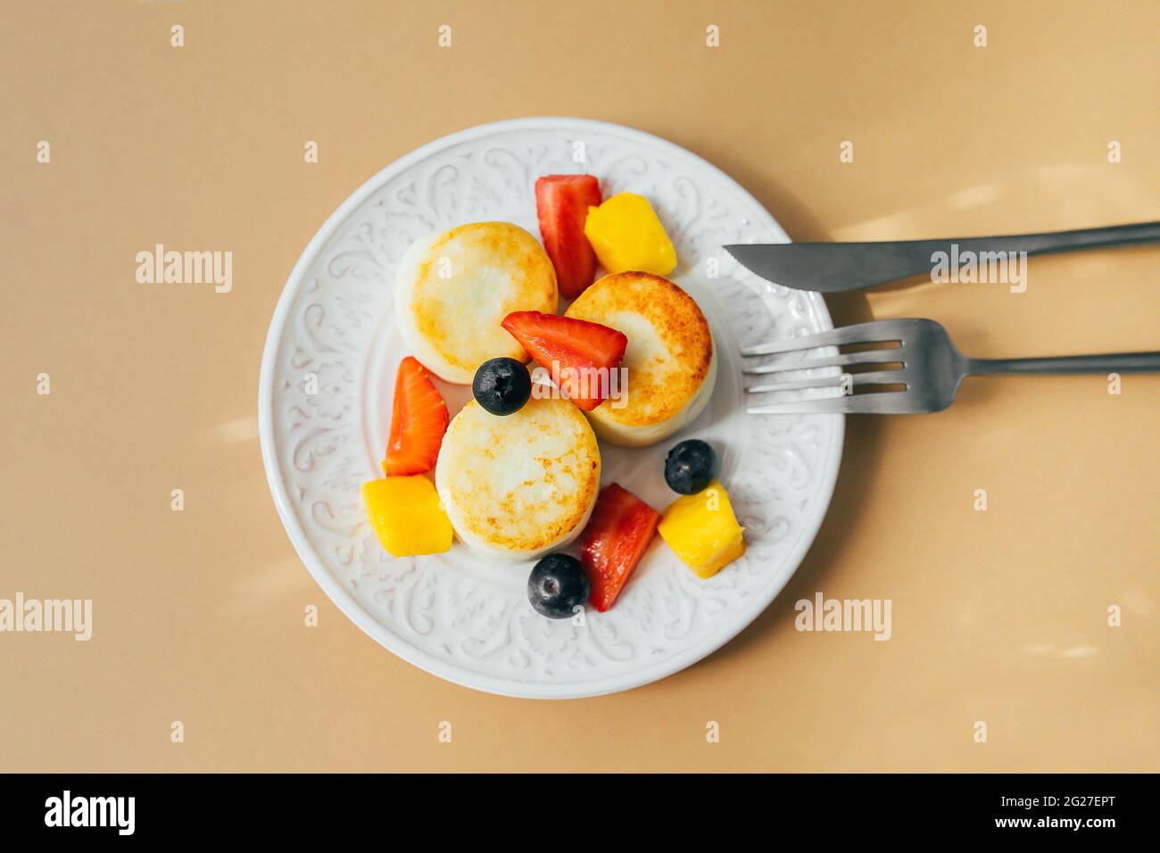 Concetto di cibo per la colazione. Frittelle al formaggio sul piatto. Syrniki con frutti di bosco, vista dall'alto. Foto Stock