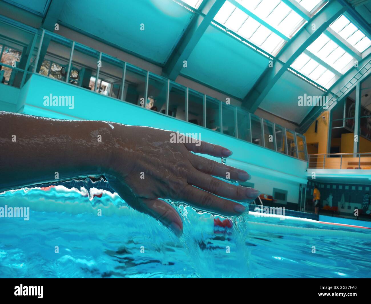 Piscina sportiva con acque turchesi limpide. La mano della donna nel processo di nuoto con l'acqua che scorre dalle dita Foto Stock