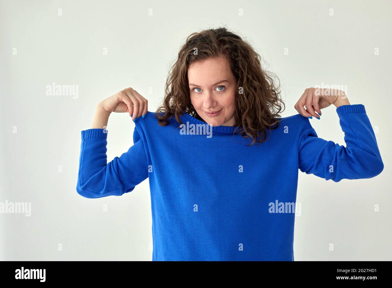 Giovane modello femminile in felpa blu oversize alla moda che guarda la fotocamera su sfondo bianco Foto Stock