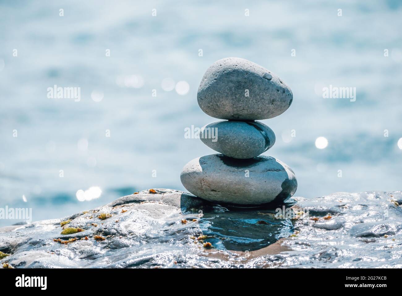 Equilibrata piramide di ciottoli sulla spiaggia in una giornata di sole. Abstract Sea bokeh sullo sfondo. Messa a fuoco selettiva. Pietre Zen sulla spiaggia di mare, meditazione Foto Stock