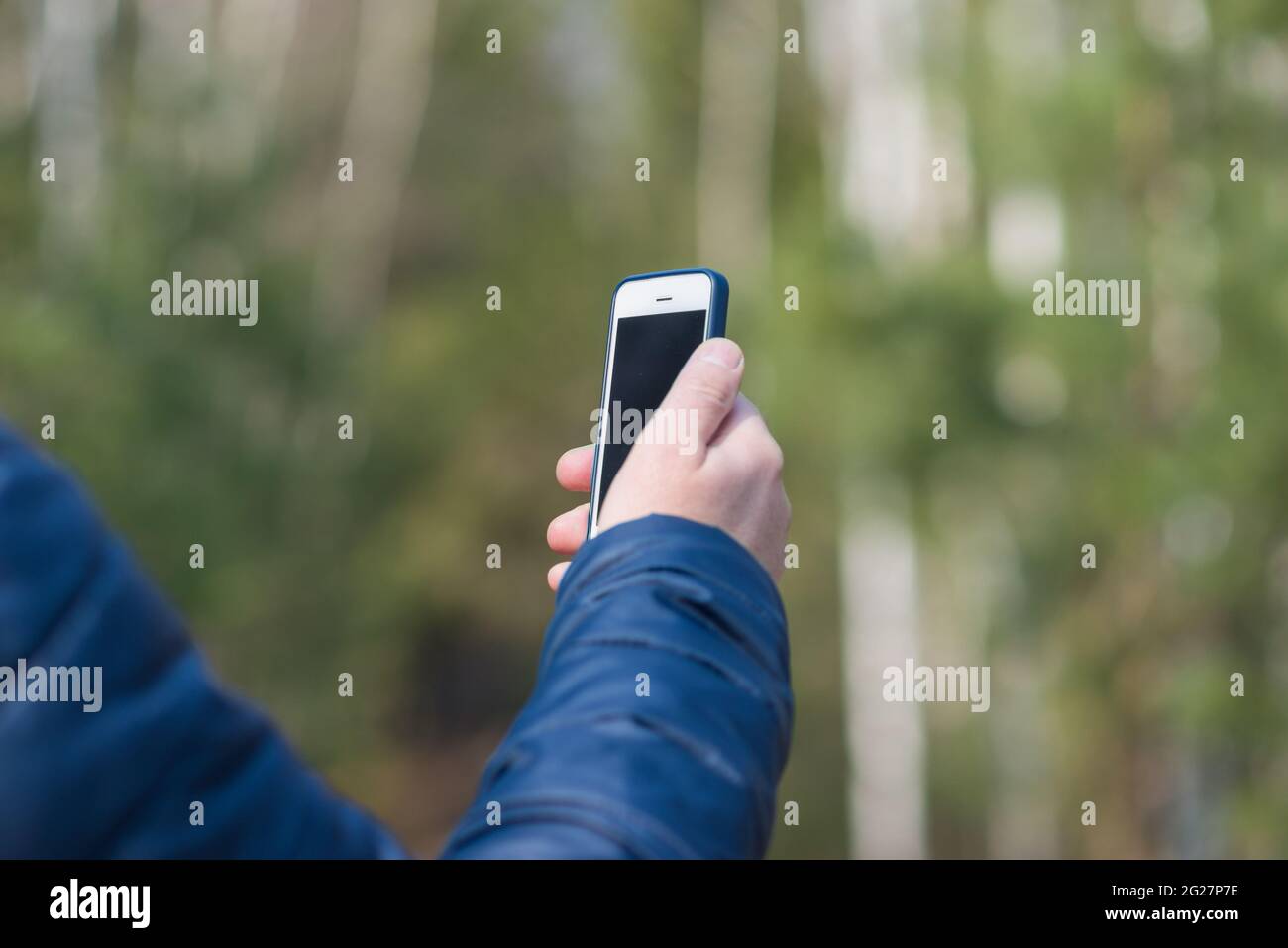 Un uomo di 40 anni con il suo smartphone cellulare alla ricerca del segnale di ricezione nella foresta primaverile. Foto Stock