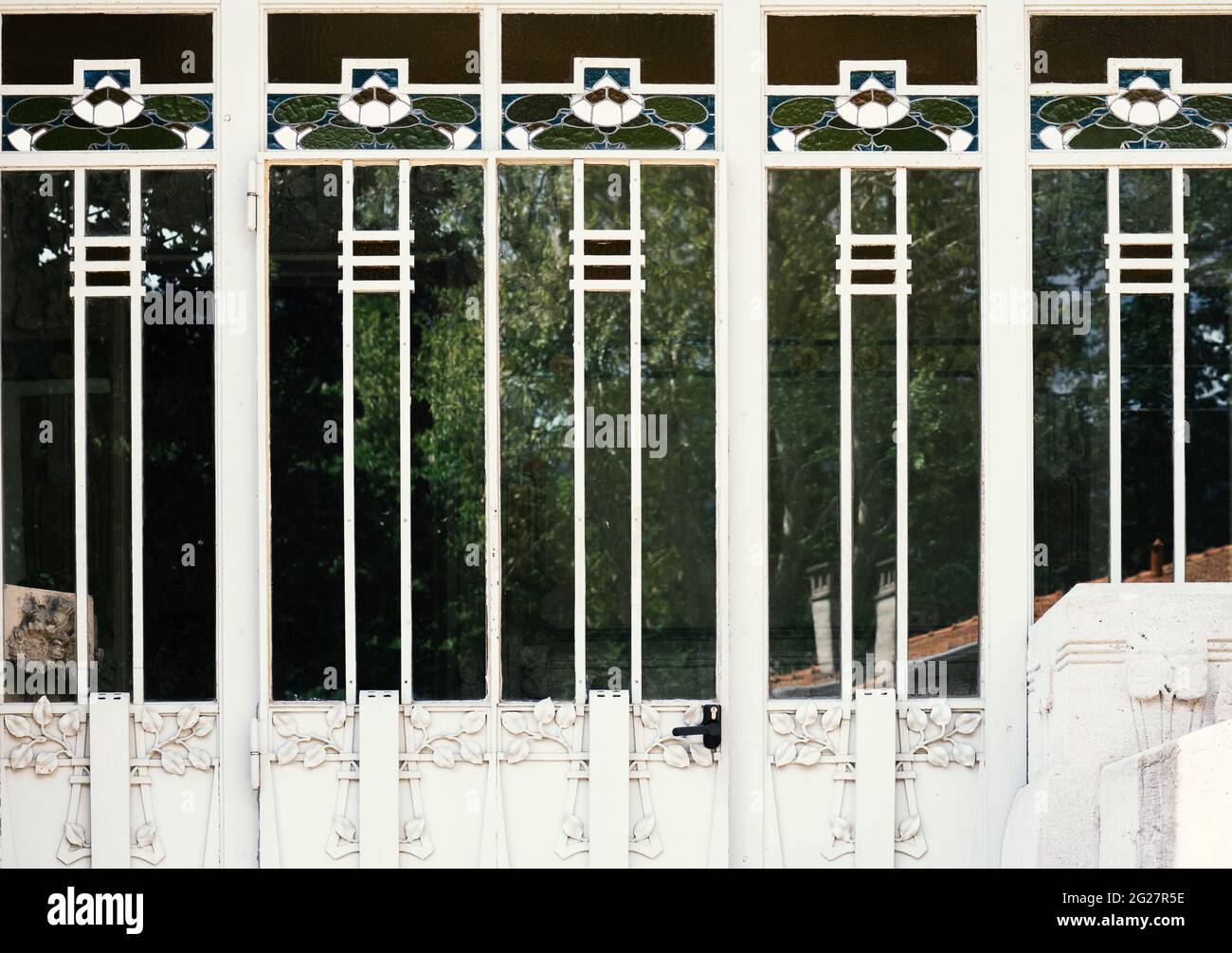 particolare di una porta in legno bianco con vetro e ferro battuto a motivi floreali Foto Stock