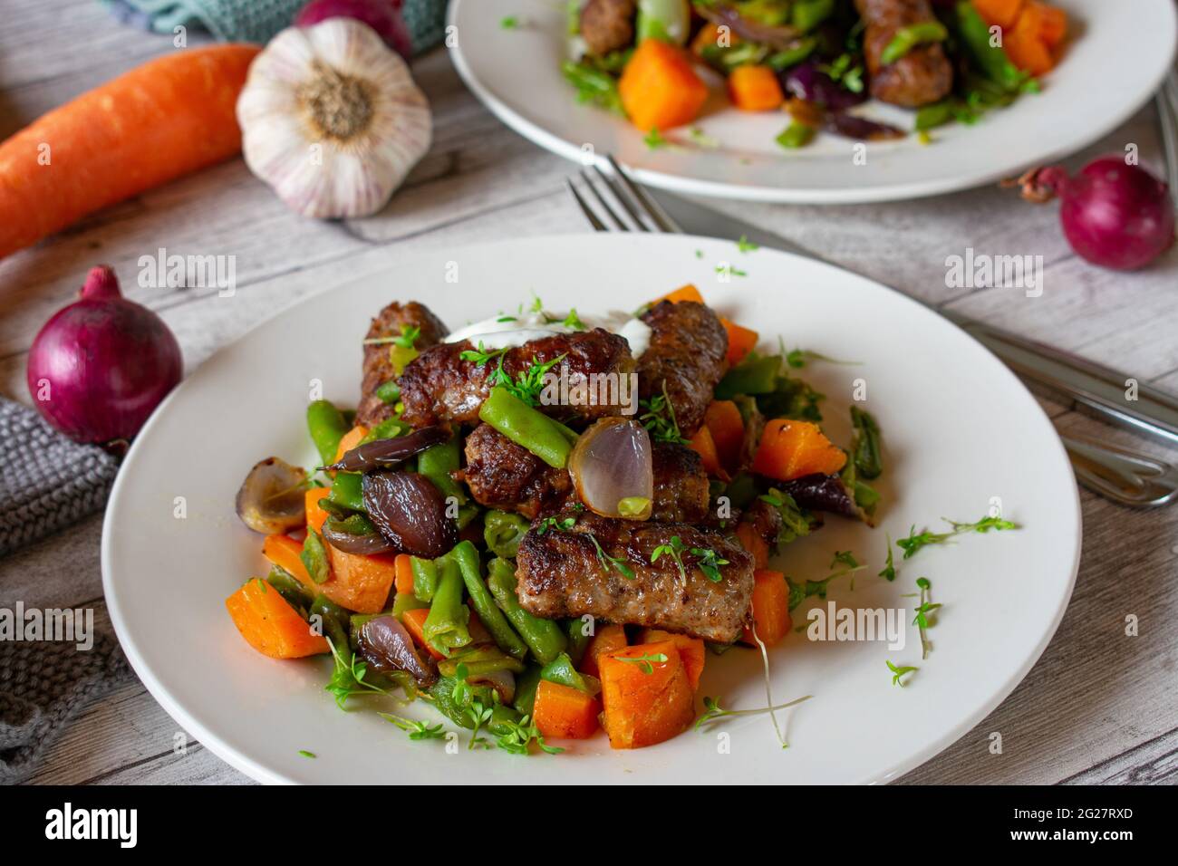 Piatto a base di carb con rools di carne piccanti e verdure servito con una salsa di yogurt fresco su un piatto su tavola rustica dietro Foto Stock