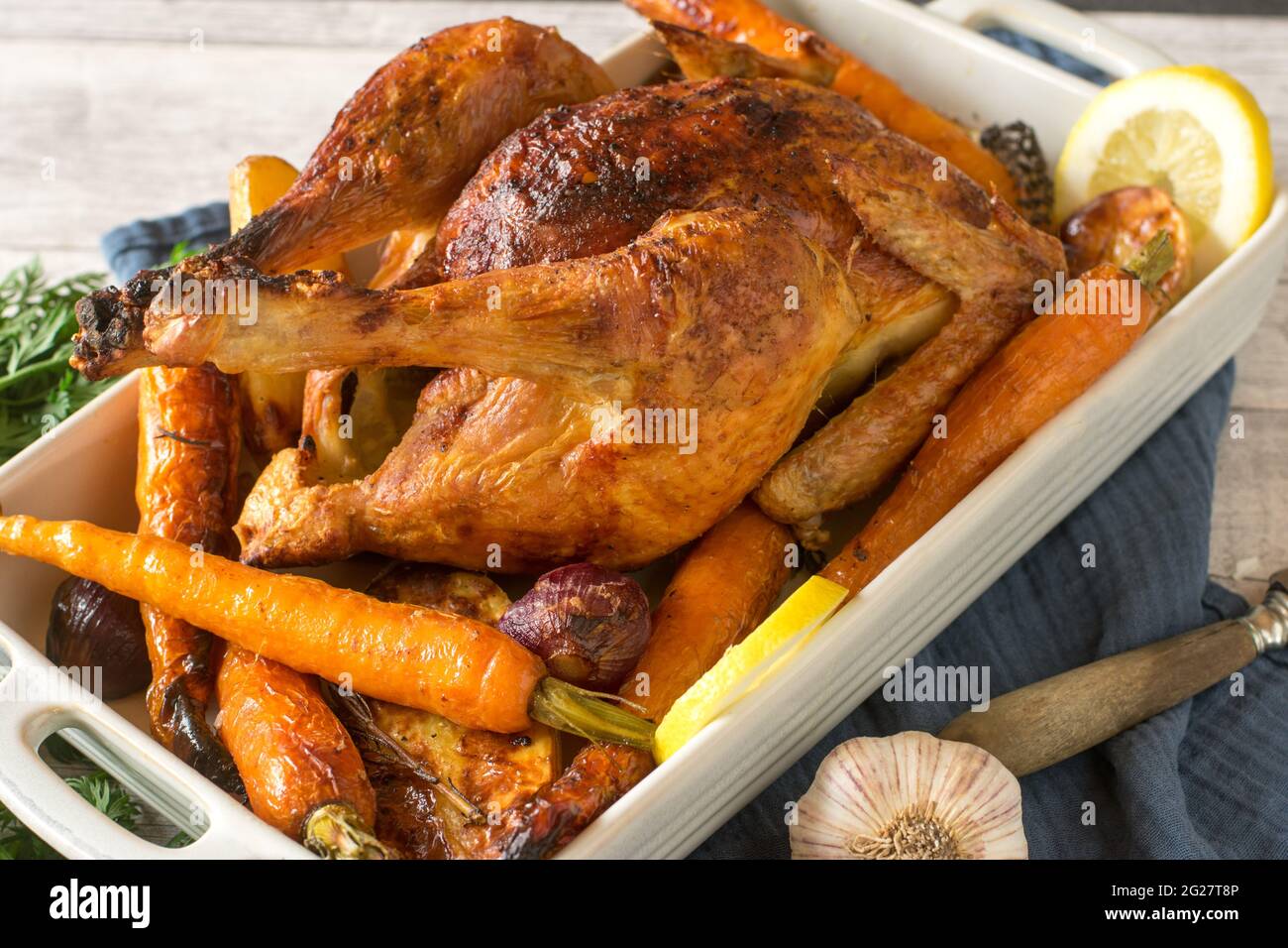 Pollo arrosto con verdure al forno servito in una teglia su sfondo rustico e in legno. Primo piano e vista isolata Foto Stock