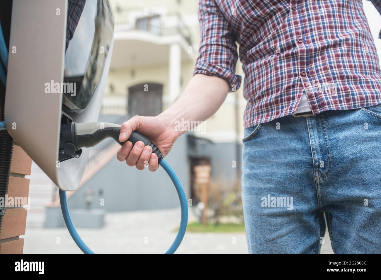 Uomo vicino alla stazione di ricarica in proprietà privata Foto Stock