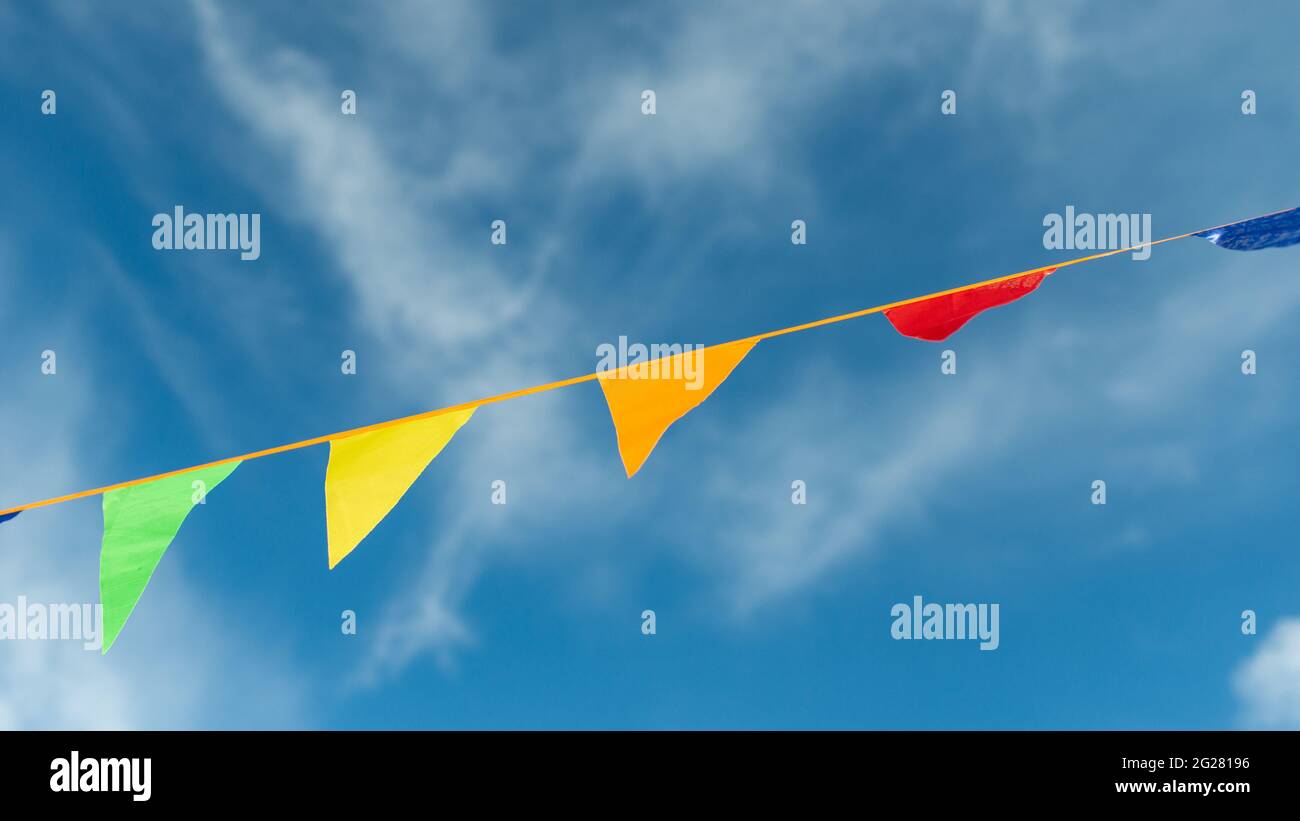 Triangoli colorati su un nastro si innalzano nell'aria contro il cielo. Foto Stock