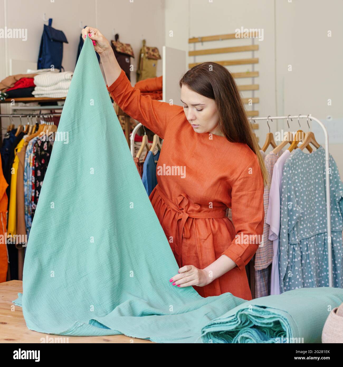 Donna stilista di moda misura tessuto mentre lavora in studio di cucito Foto Stock