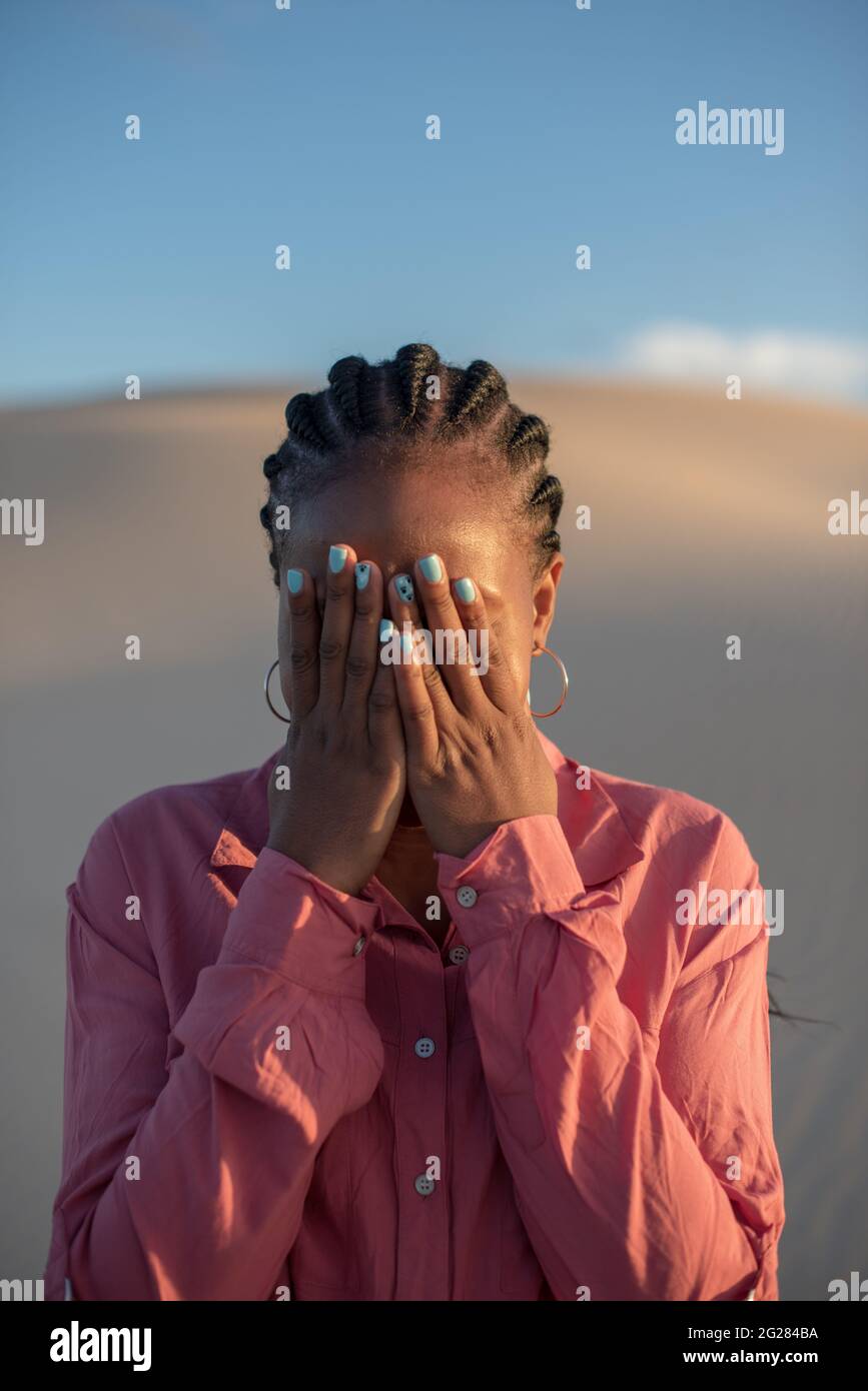 Primo piano di una donna che si nasconde dietro le mani Foto Stock