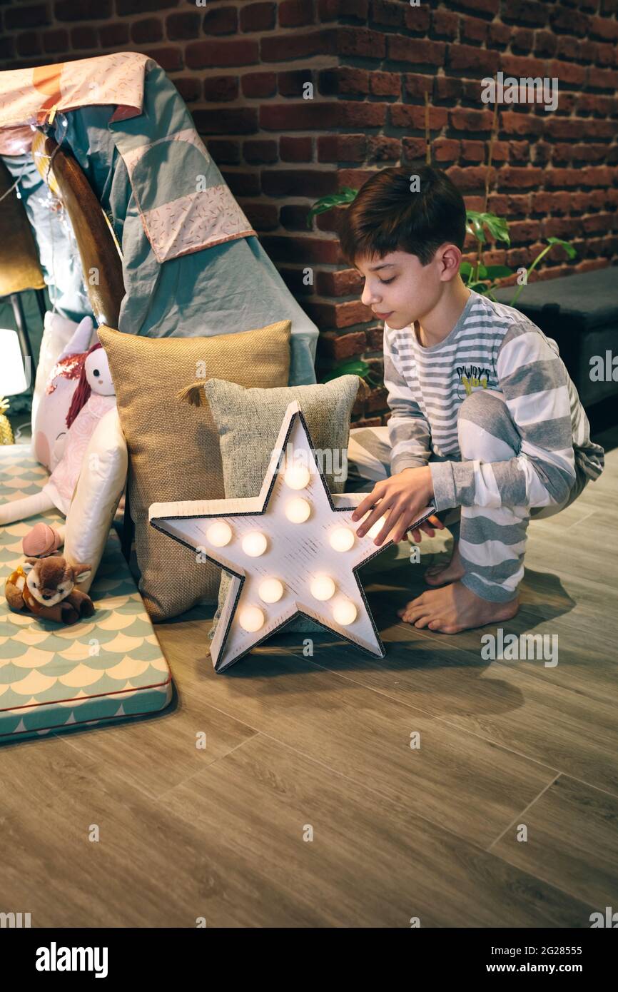 Teen maschio che mette una lampada della stella che aiuta a preparare una festa di sonno Foto Stock