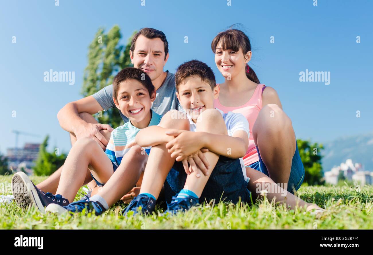 Famiglia vestita di bianco nel parco in estate seduta in Prato Foto Stock