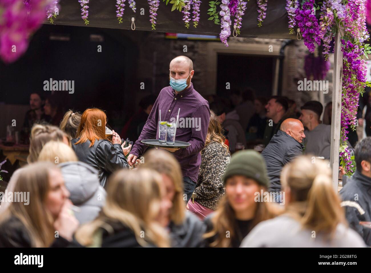 I server portano bevande ai tavoli delle 3 Sorelle di Edimburgo, in quanto i pub possono servire all'esterno dopo essere stati chiusi a causa dell'epidemia di covid-19. Credito: Euan Cherry Foto Stock