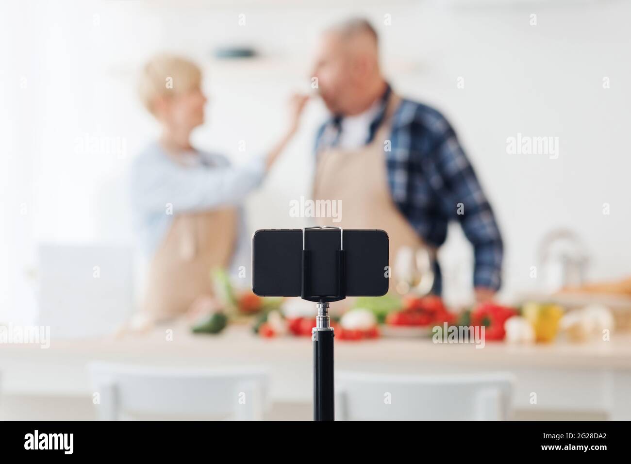 Blogger che assaggia cibo, famiglia che insegna a cucinare mangiare sano e girare video su smartphone webcam Foto Stock