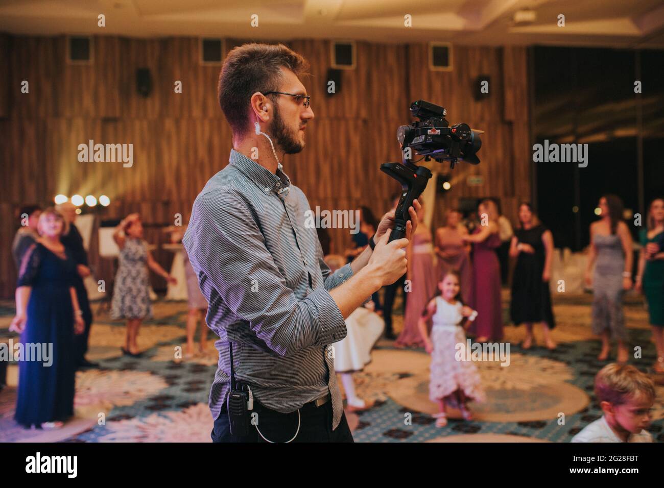 Bel cameraman in occhiali che sparano un matrimonio Foto Stock