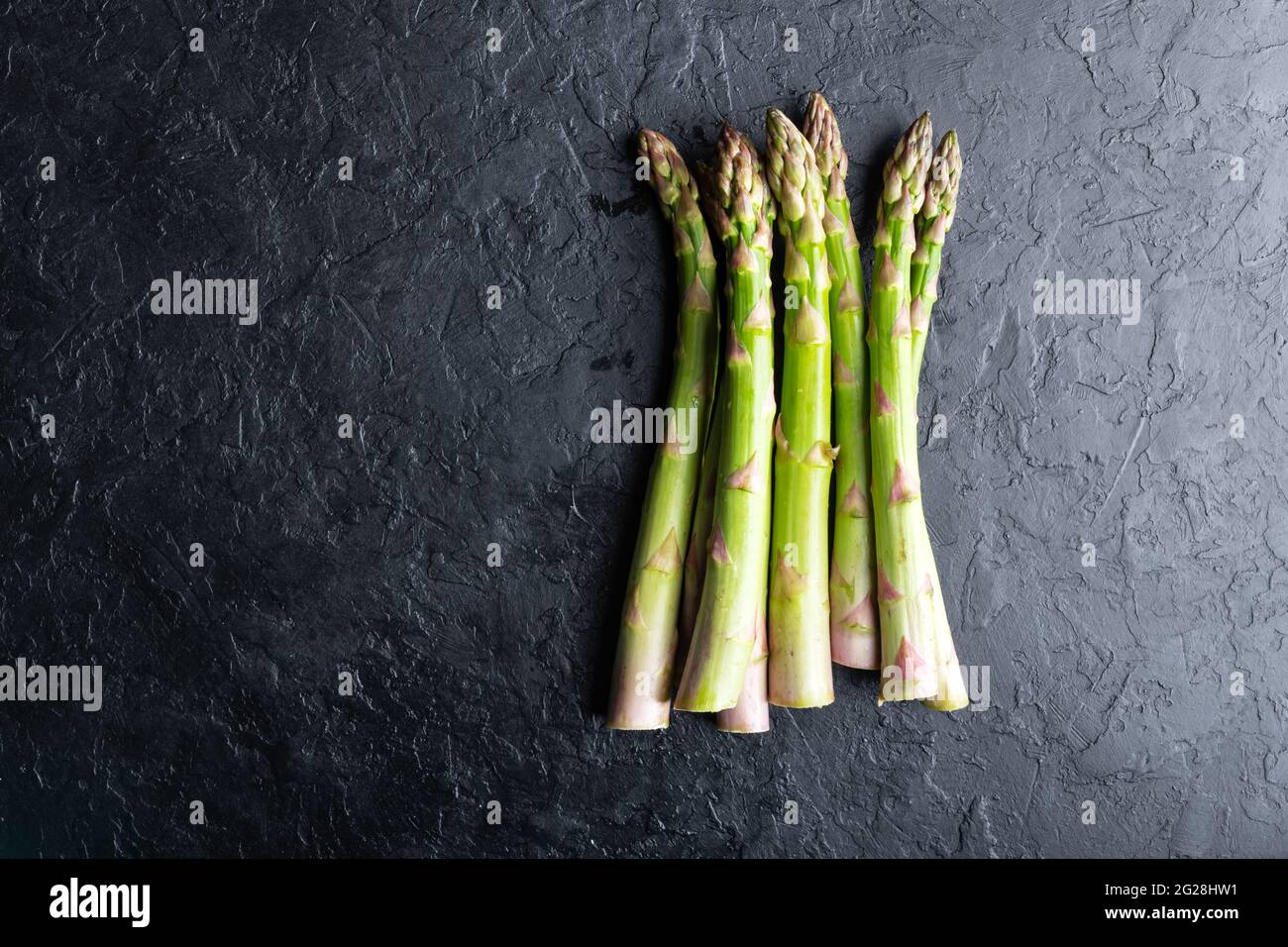Germogli di asparagi verdi su tavola nera vista dall'alto piatto. Fotografia alimentare Foto Stock