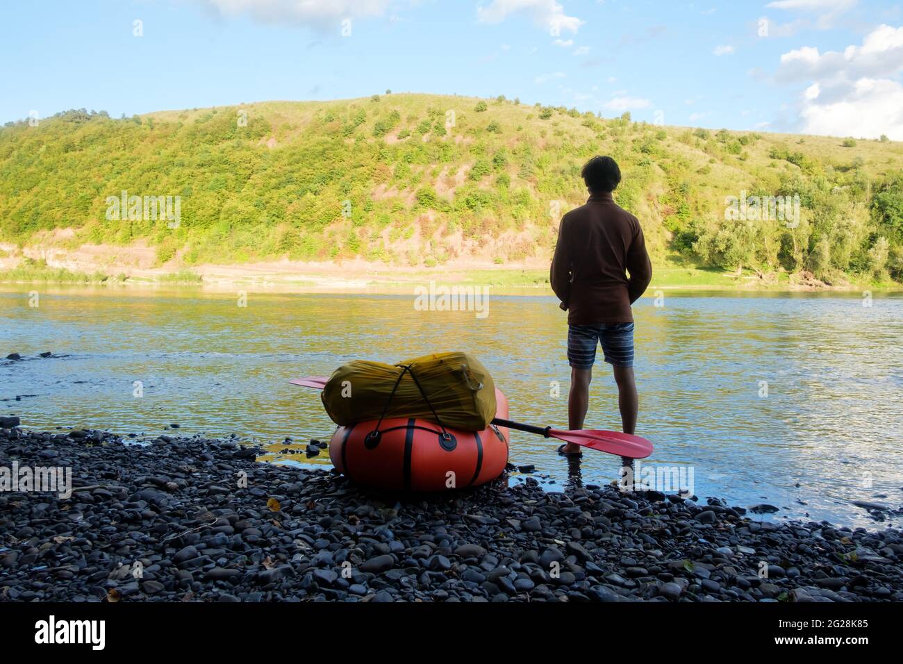 Turistico vicino a packraft giallo barca di gomma pronta per le avventure con padle rosso su un fiume alba. Packrafting. Concetto di vita attiva Foto Stock