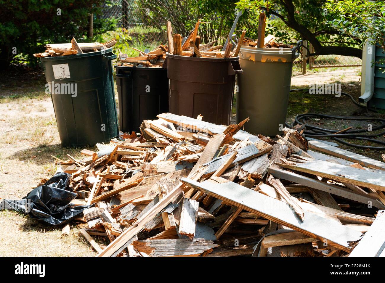 Pile di legno a terra e in chiodi spazzatura sinistra dalla rimozione di un ponte di legno in un cortile. Foto Stock