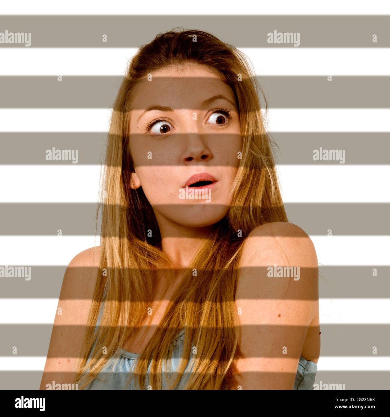 Immagine migliorata digitalmente di una giovane ragazza sorpresa illuminata attraverso le tende dell'otturatore Foto Stock
