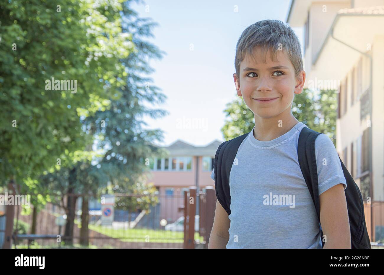 Lo scolaro torna a scuola. Ha sorriso. Dietro le spalle all'allievo una borsa a mano. Foto Stock