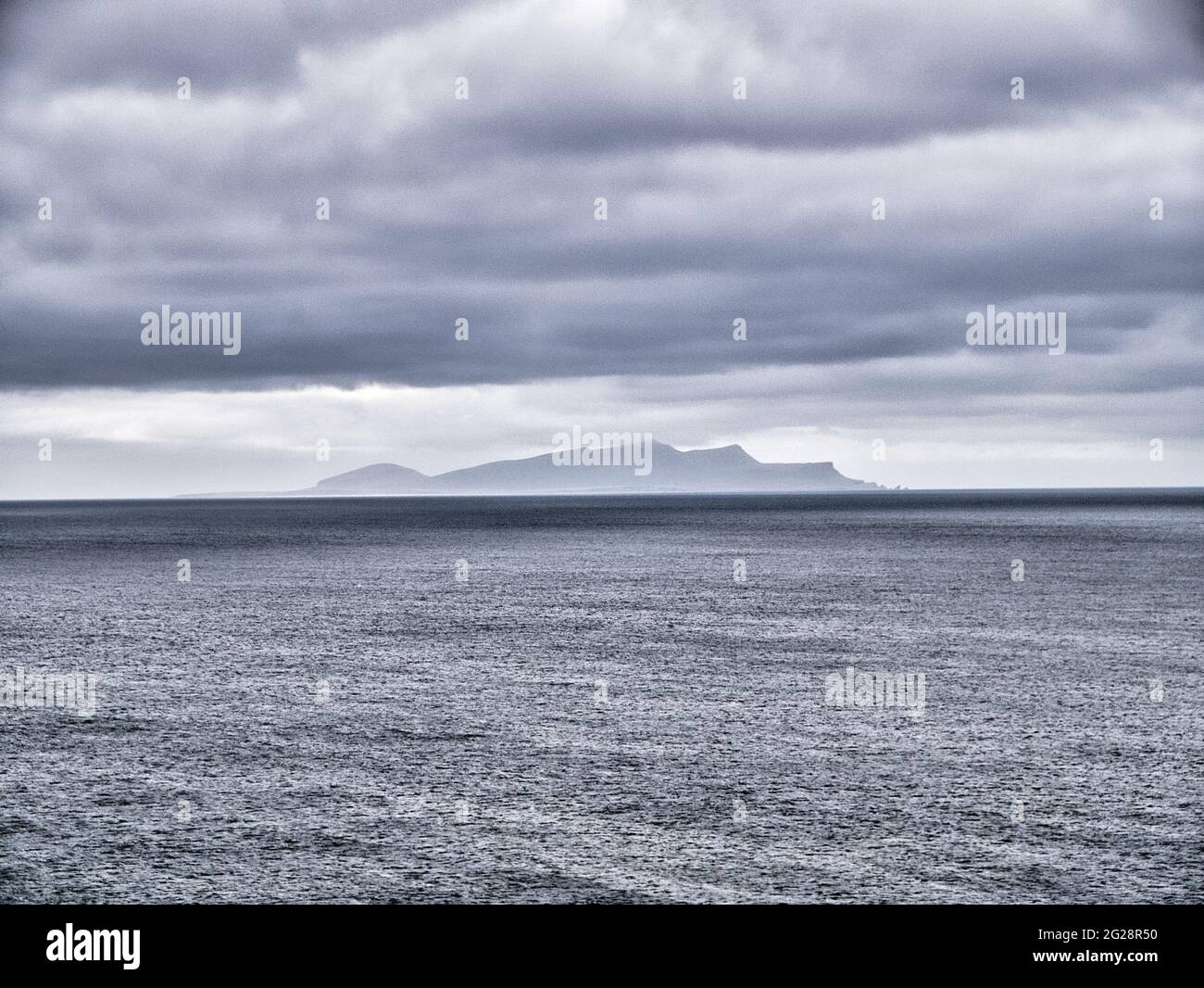 Con un effetto granulare indotto su una giornata fredda, grigia, sovracolata, una vista attraverso un mare calmo fino all'isola Shetland di Foula. Foto Stock