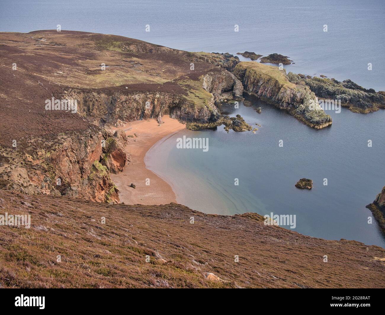 In una giornata tranquilla sotto il sole, la spiaggia di sabbia rossa incontaminata a Bungil, su Muckle Roe, Shetland, Regno Unito Foto Stock