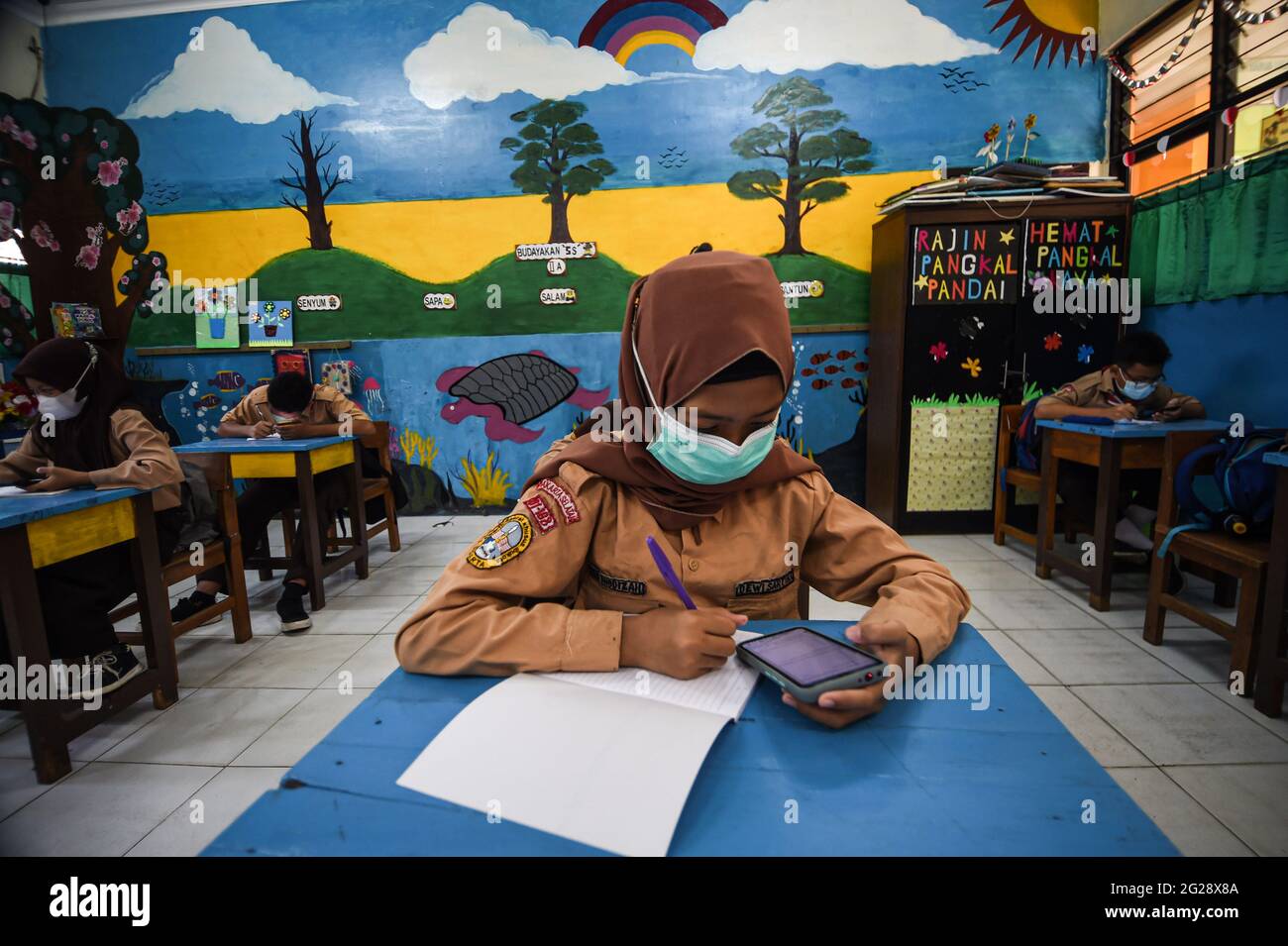 Giacarta, Indonesia. 9 Giugno 2021. Gli studenti elementari che indossano maschere facciali vengono visti in classe durante un'attività di apprendimento faccia a faccia in occasione dell'epidemia di COVID-19 in una scuola di Giacarta, Indonesia, il 9 giugno 2021. Credit: Agung Kuncahya B./Xinhua/Alamy Live News Foto Stock